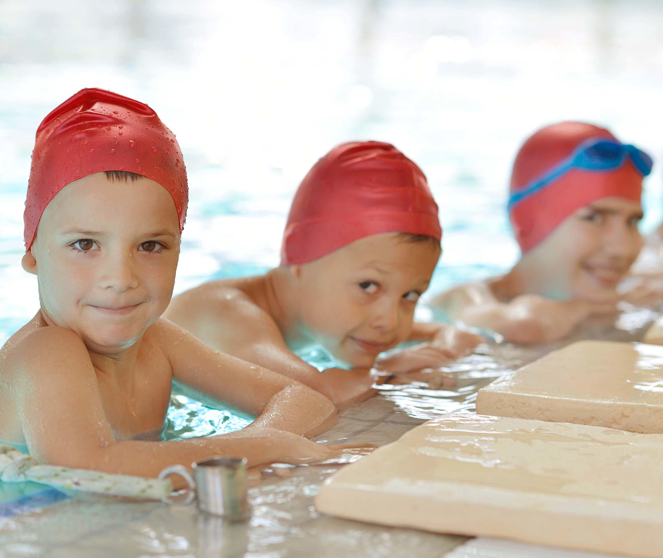 Kinder am Schwimmbeckenrand lächeln in die Kamera